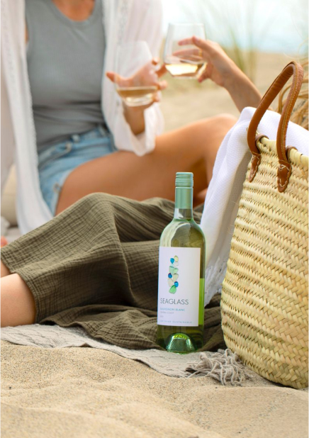 Two friends enjoy a bottle of Seaglass sauvignon blanc white wine on a beach
