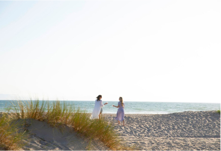 Two women in the distance drinking wine on a sunny, sandy beach